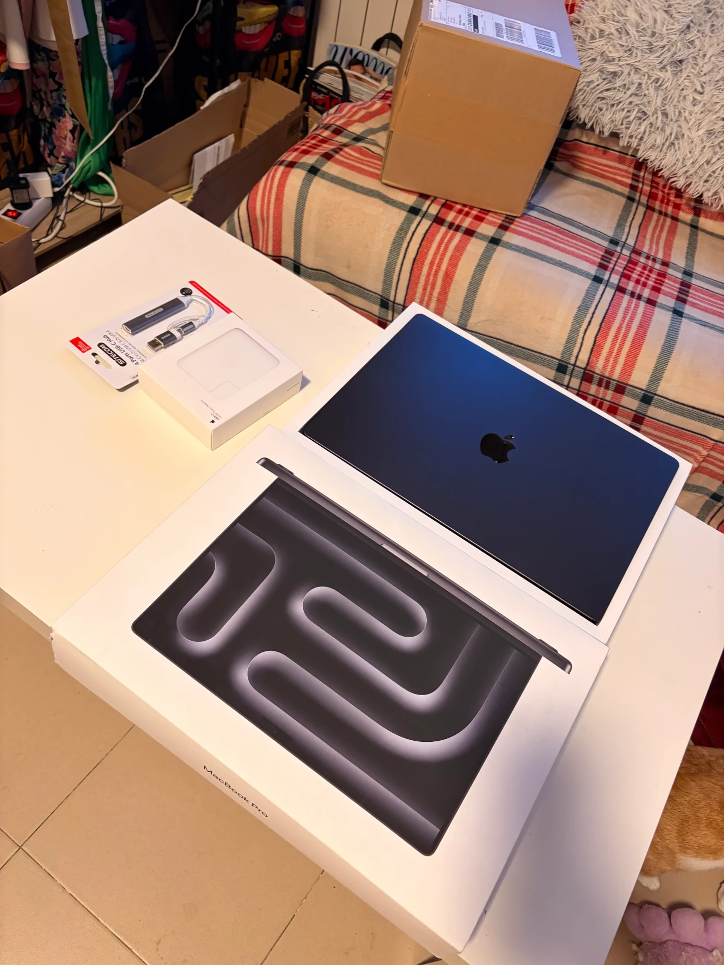 Cartons ouverts sur une table avec un MacBook Pro et des accessoires